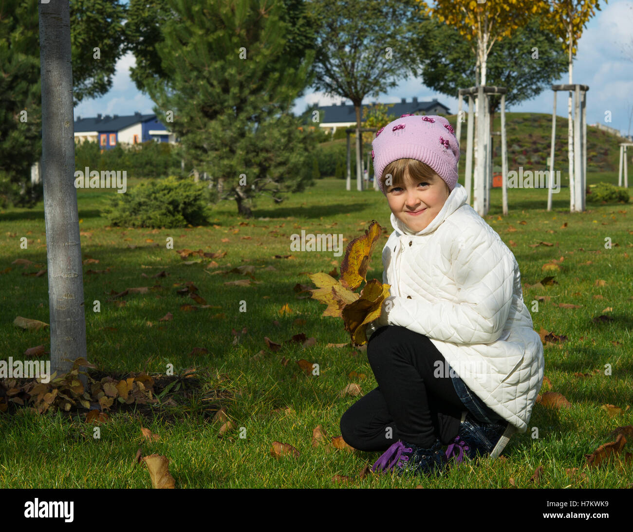 kleines Mädchen auf der Wiese im Herbst sammelt Blätter Stockfoto