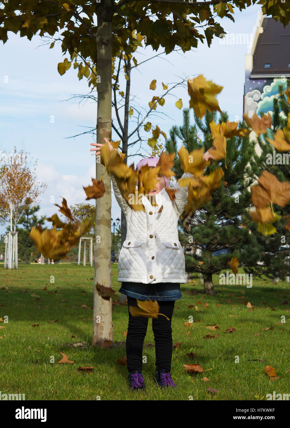 kleines Mädchen wirft Blätter Stockfoto