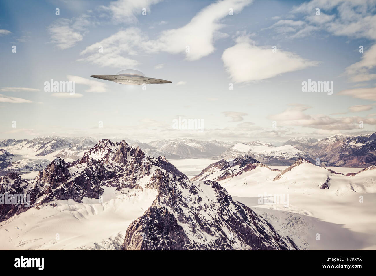UFO fliegt über Alaska Bergwildnis mit Wolken. Stockfoto