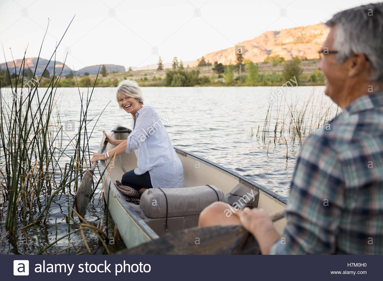 Ehepaar im Ruhestand zu lachen und Kanufahren auf ruhiger See Stockfoto