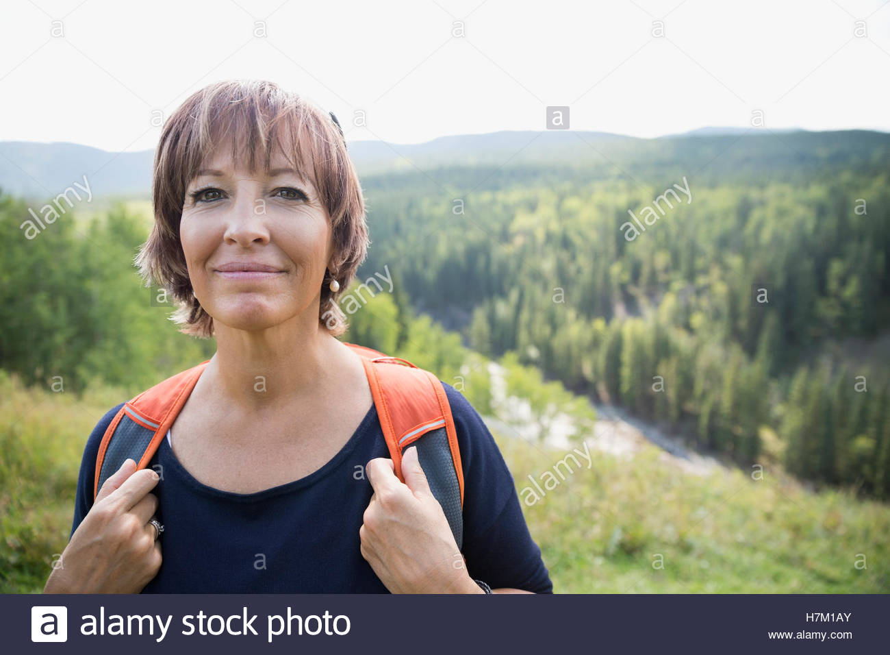 Porträt lächelnd Reife Frau mit Rucksack wandern auf abgelegenen ländlichen Sonnenhang Stockfoto