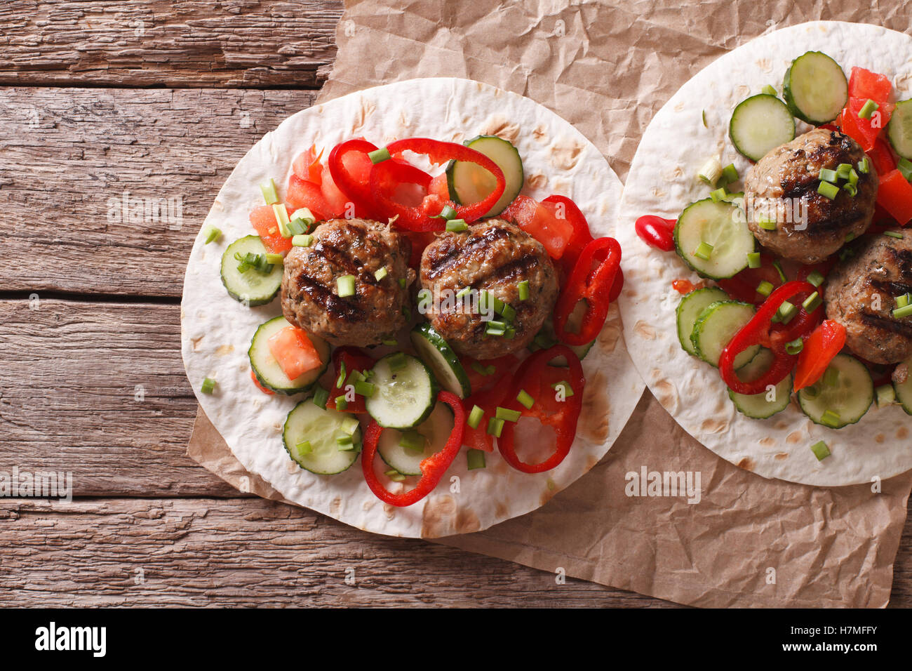 Gegrillte Frikadellen mit frischem Gemüse auf ein flaches Brot auf dem Tisch. horizontale Ansicht von oben Stockfoto