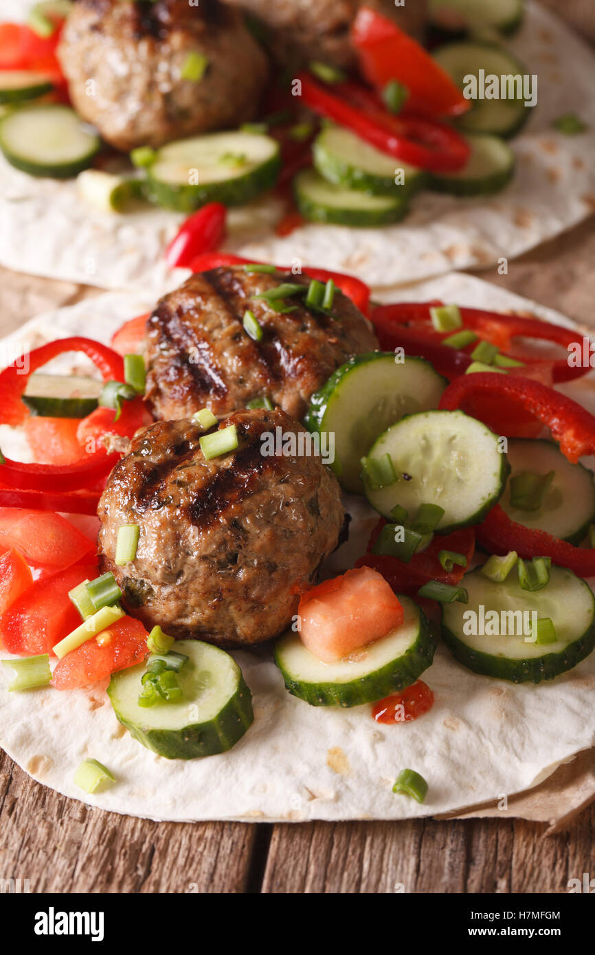 Türkische Kofta mit frischem Gemüse auf ein flaches Brot hautnah auf dem Tisch. Vertikal Stockfoto