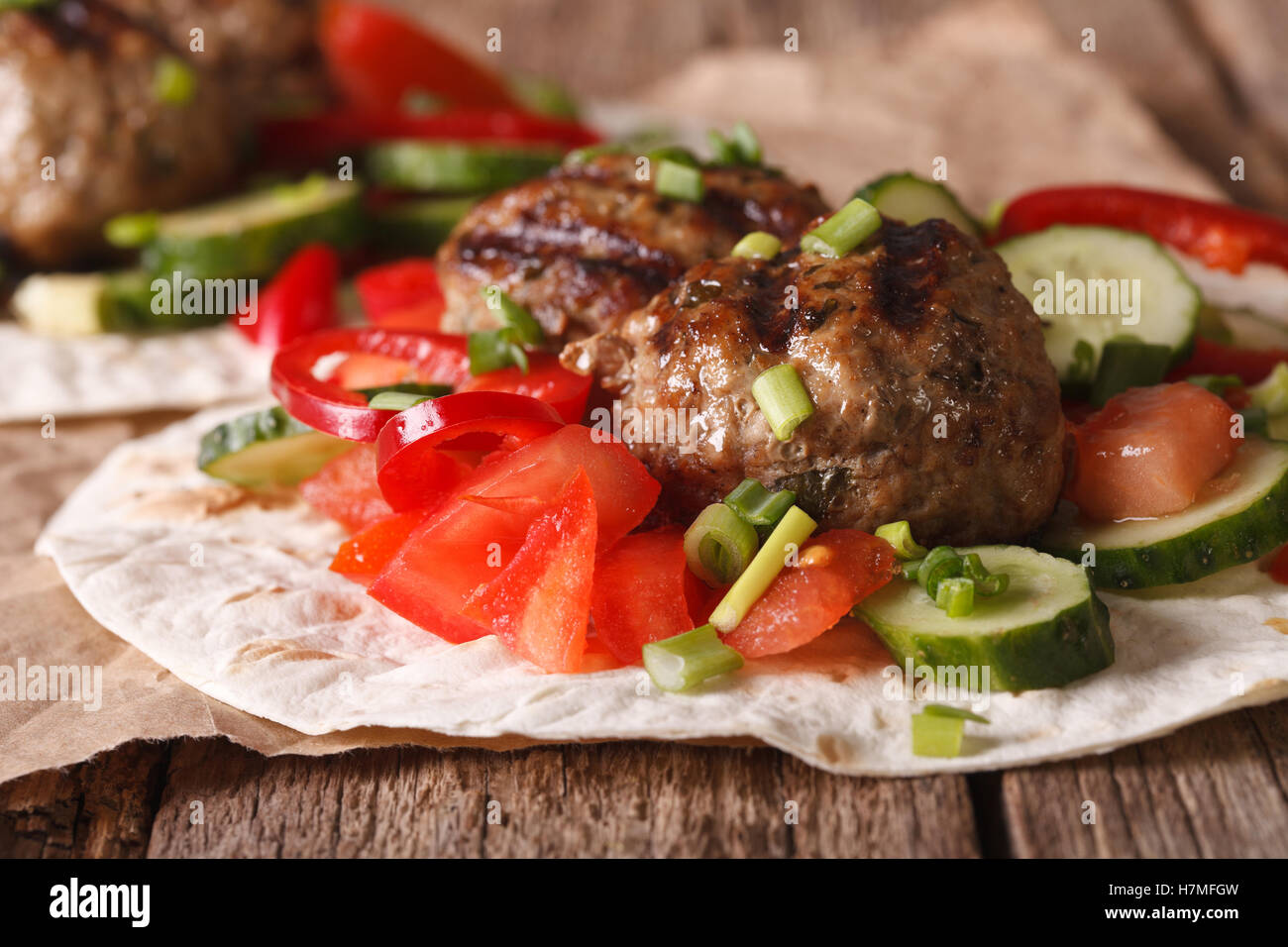 Türkische Kofta mit frischem Gemüse auf ein flaches Brot hautnah auf dem Tisch. horizontale Stockfoto