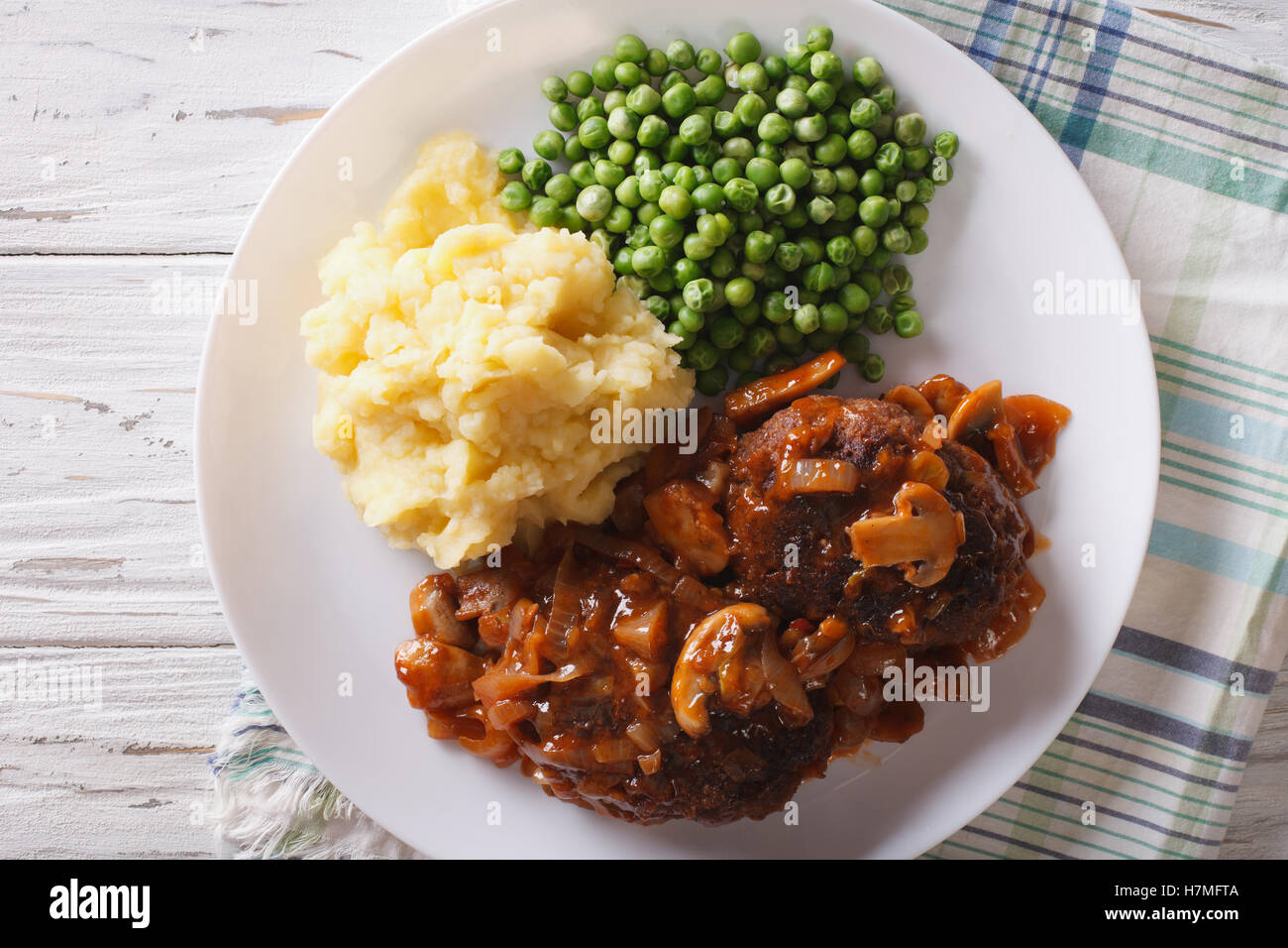 Salisbury Steak mit Kartoffeln und Erbsen-close-up auf einem Teller auf den Tisch. horizontale Ansicht von oben Stockfoto