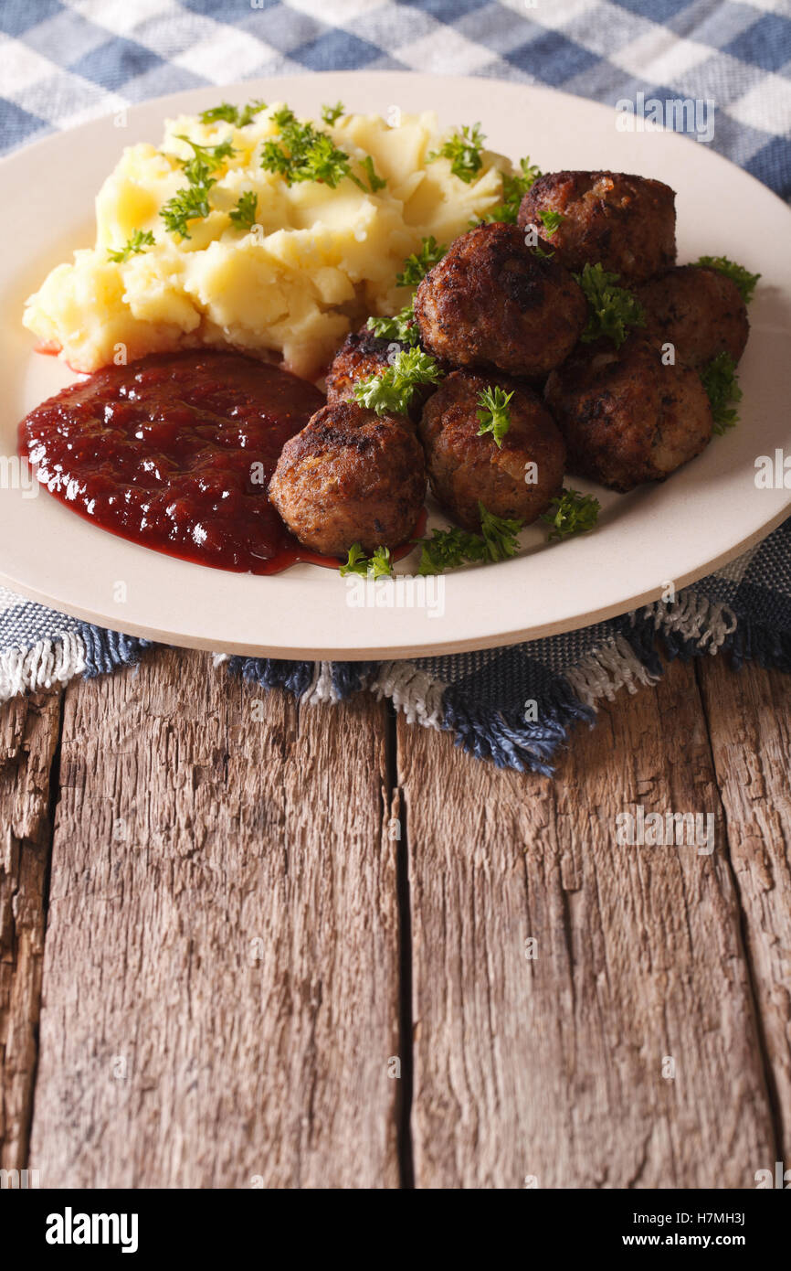 Schwedische Fleischbällchen Kottbullar, Preiselbeer-Sauce mit Beilage Kartoffelpüree auf der Platte Nahaufnahme. Vertikal Stockfoto
