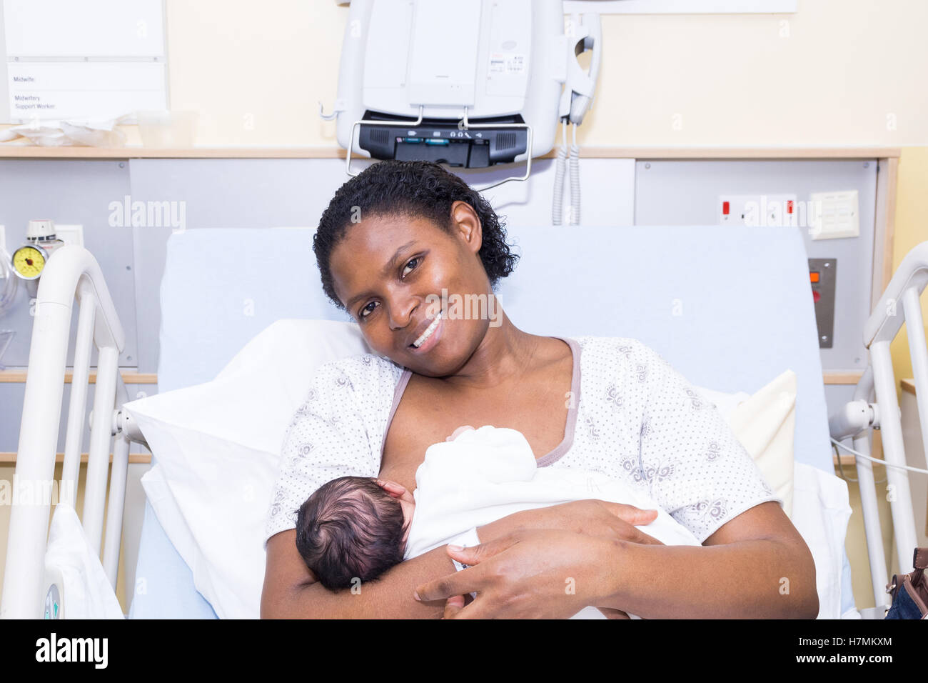 Eine stillende Mutter ihr neugeborenes Baby in einem Krankenhausbett Stockfoto