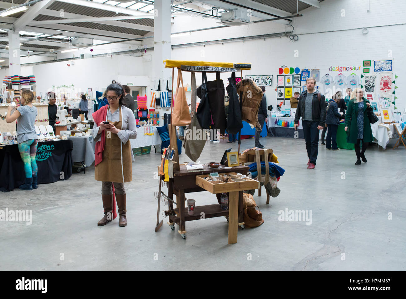 Junge Designer hinter einem Stall zu verkaufen handgefertigte Kleidung auf der Renegade Craft Fair, ein indoor Indie Designer Markt jährliches Ereignis Stockfoto