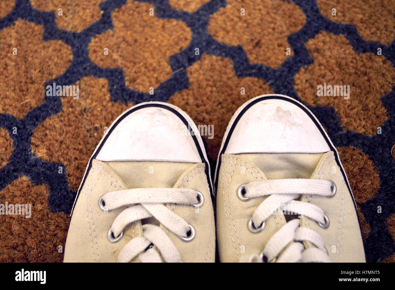 Leicht verschmutzte Converse All Star Turnschuhe auf eine Fußmatte Stockfoto