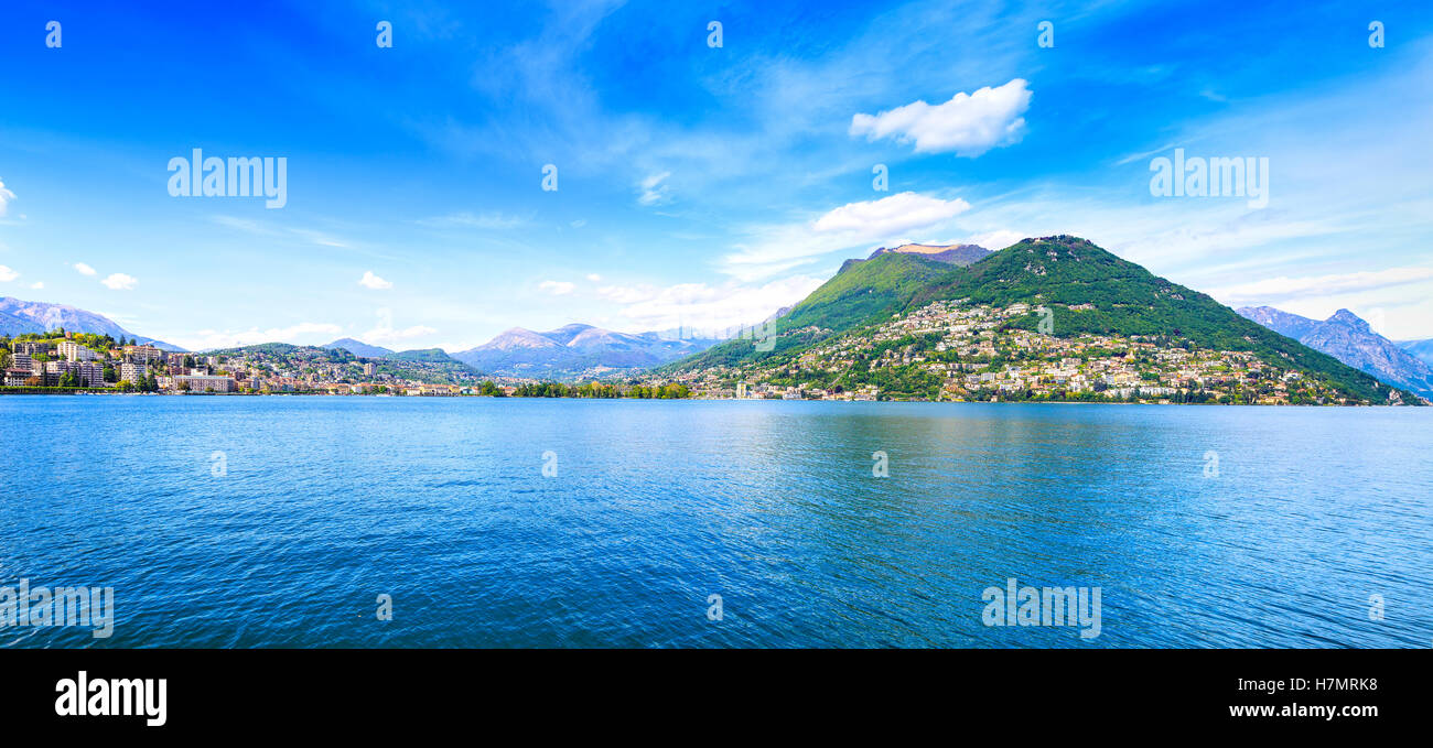 Luganer See-Panorama-Landschaft. Stadt, Seewasser, blauer Himmel und Berge. Tessin, Schweizer oder in der Schweiz, Europa. Stockfoto