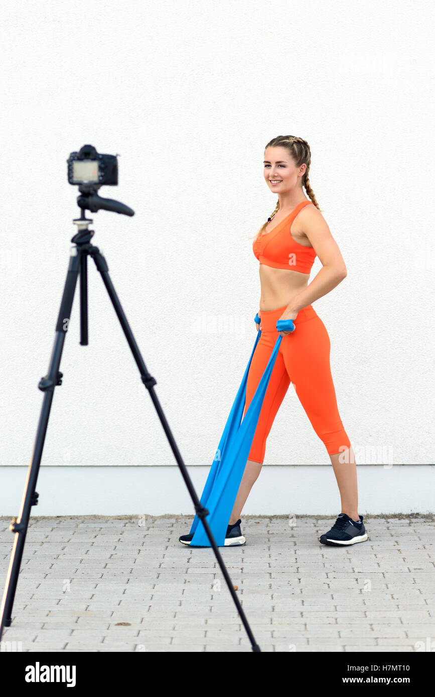 Junge sportliche Frau Videoblogger tun, Stärkung der Kern Übungen mit Latex Bänder in ein Gesundheits- und Lifestyle-Konzept, Lächeln Stockfoto