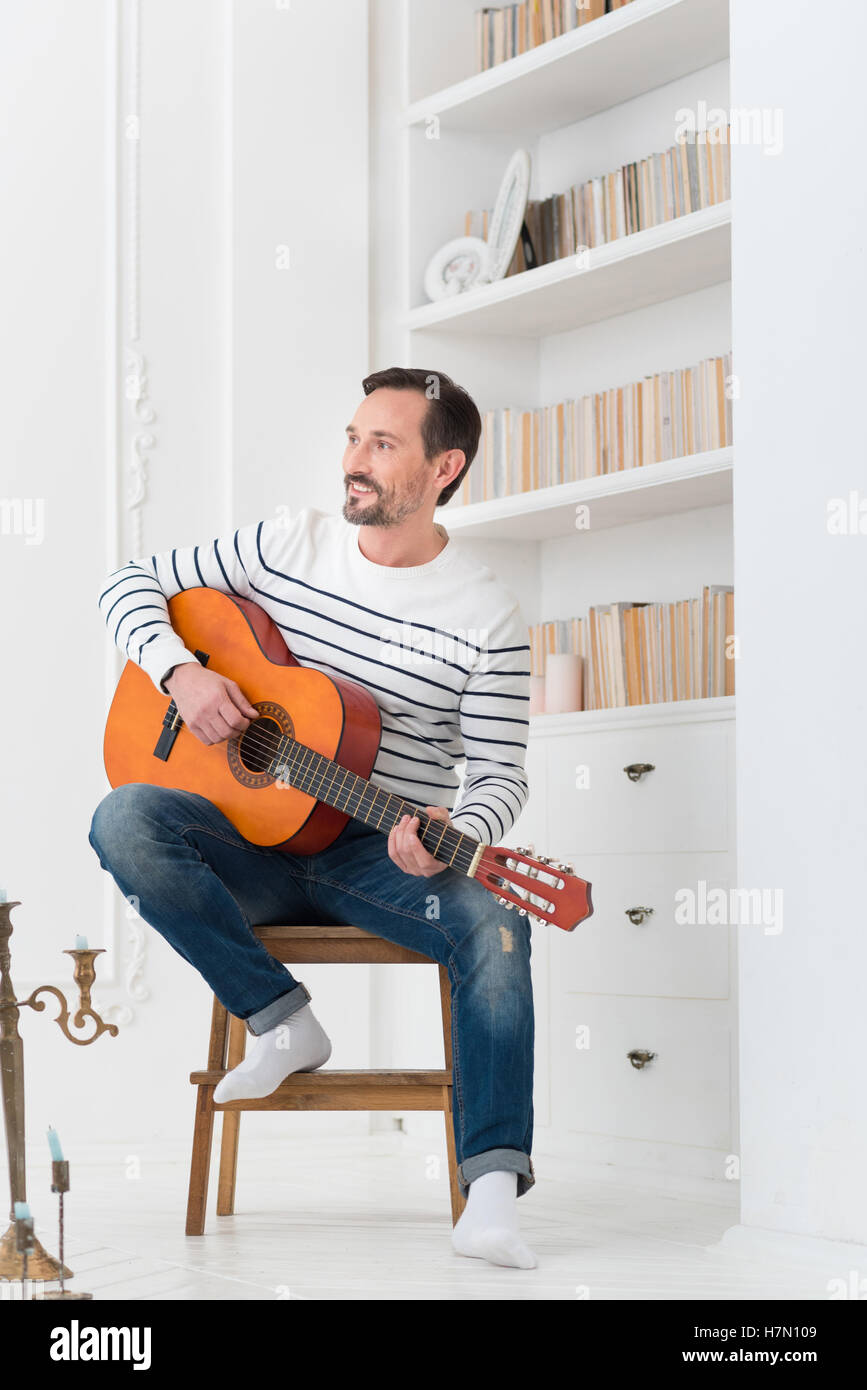 Hübscher optimistisch Mann sitzt auf dem Stuhl Stockfoto