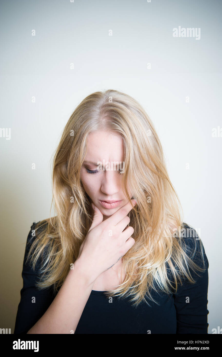 Junge blonde Frau nachdenklich blickte, vertikale Portrait mit textfreiraum auf Kopf Stockfoto