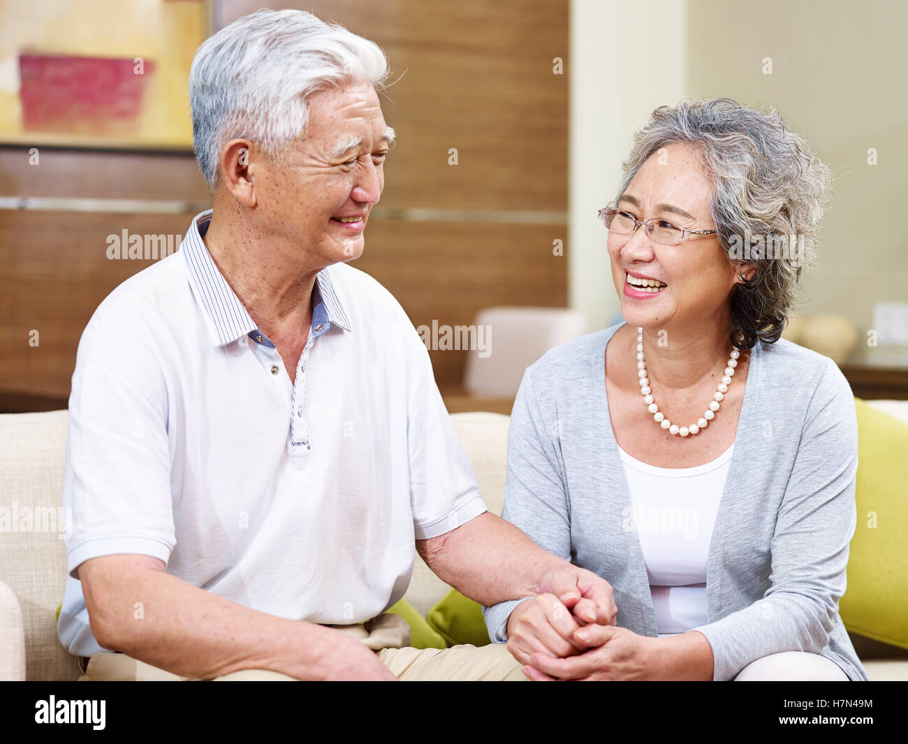 hochrangige asiatische Brautpaar sitzen auf couch zu Hause sprechen, Lächeln, Hand in Hand Stockfoto