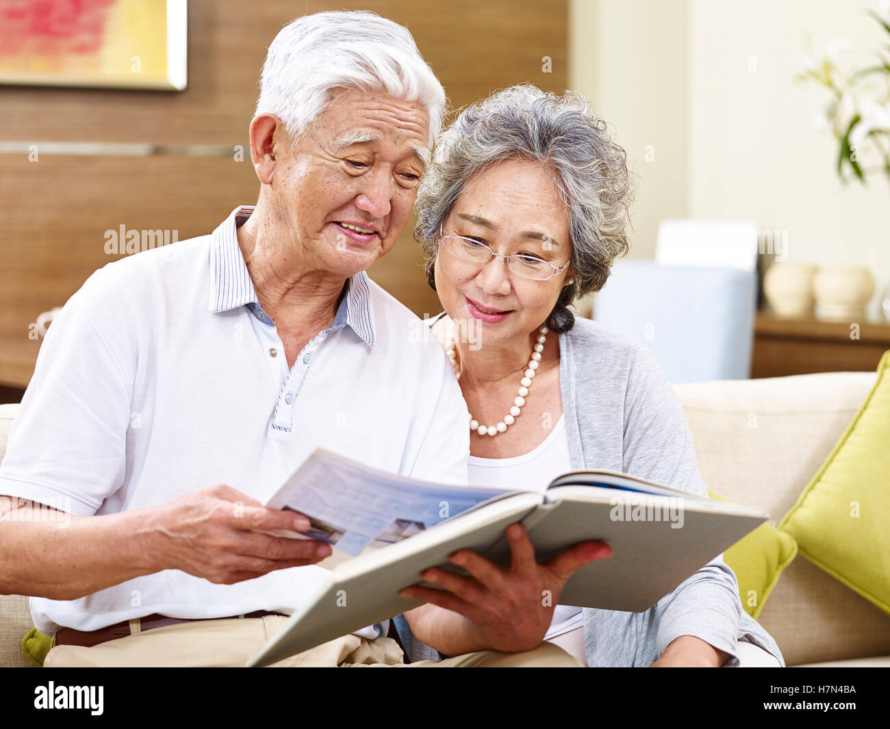 hochrangige asiatische paar auf Couch zusammen ein Buch lesen Stockfoto