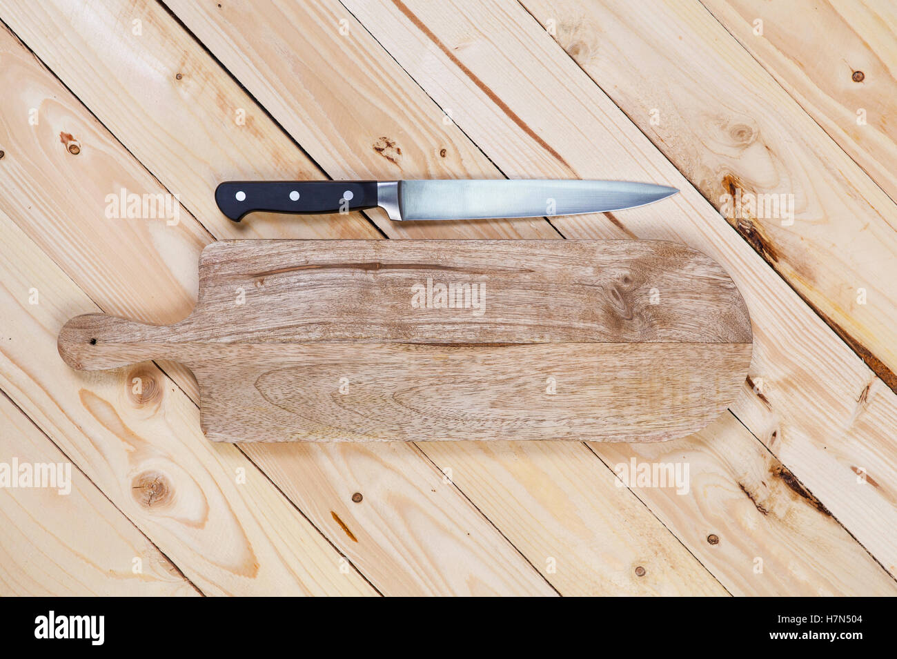 Schneidebrett mit Messer auf Holztisch. Ansicht von oben Stockfoto