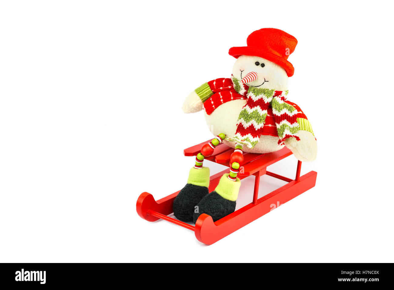 Gekleidete Schneemann Figur sitzt auf roter Schlitten isoliert auf weißem Hintergrund Stockfoto