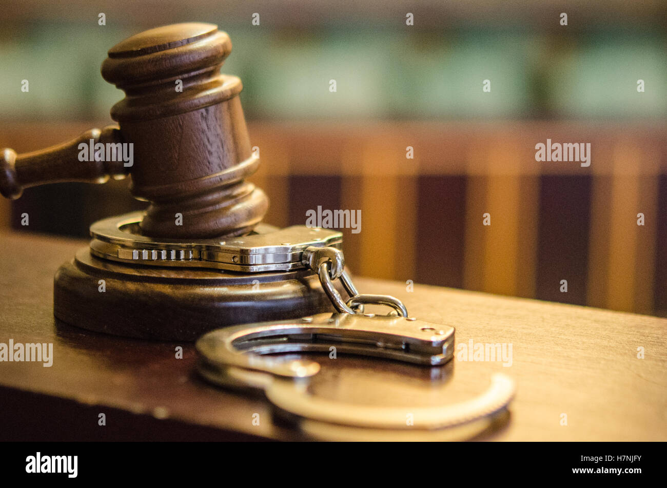 Nahaufnahme von Hammer und Handschellen auf Richters Bank im Gerichtssaal mit Jury-Box und Sitze im Hintergrund Stockfoto