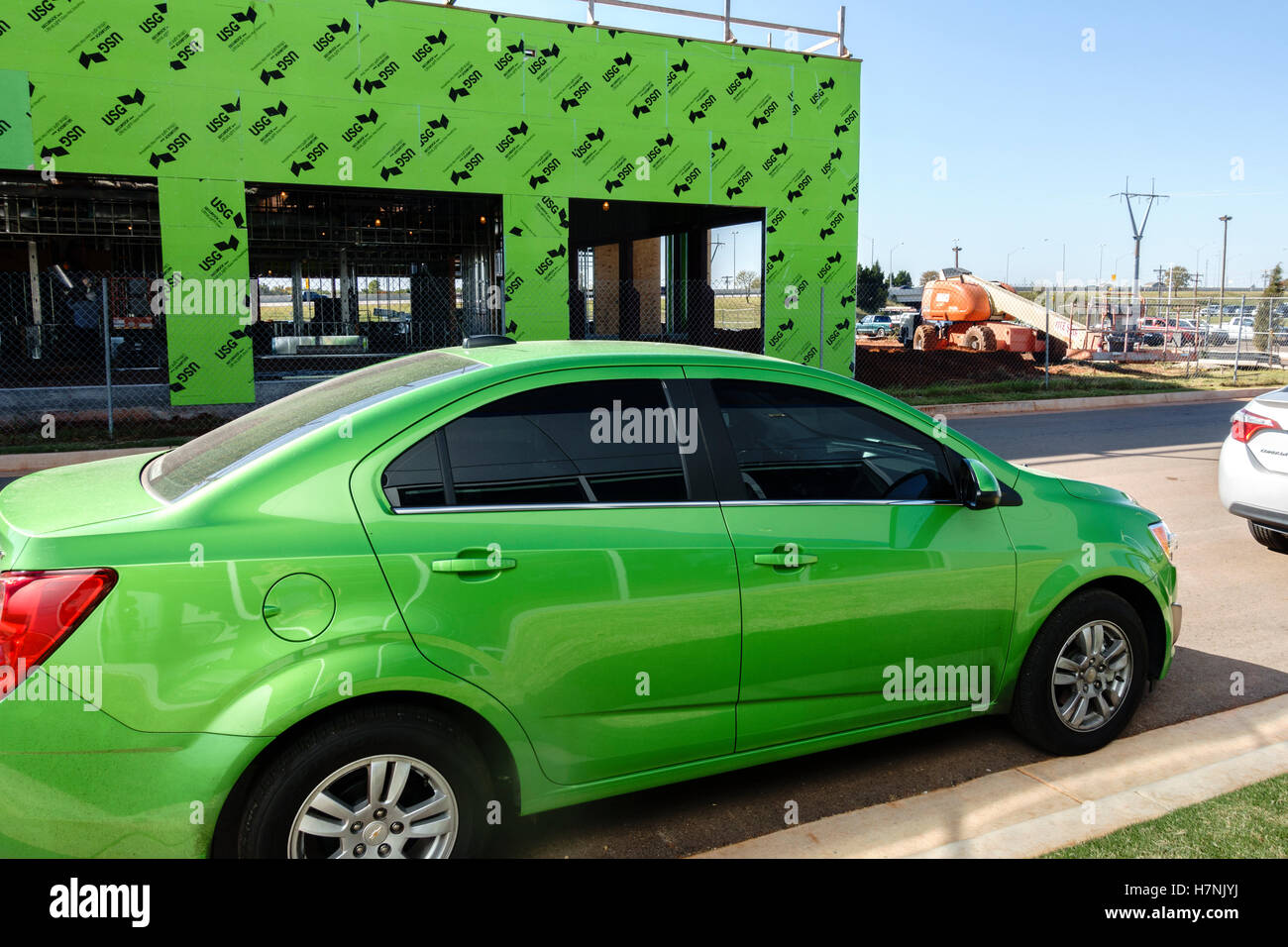 Ungewöhnliche Zusammentreffen von Lime Green passende Farben in einem Automobil und ein im Bau befindliches Gebäude. Oklahoma, USA. Stockfoto