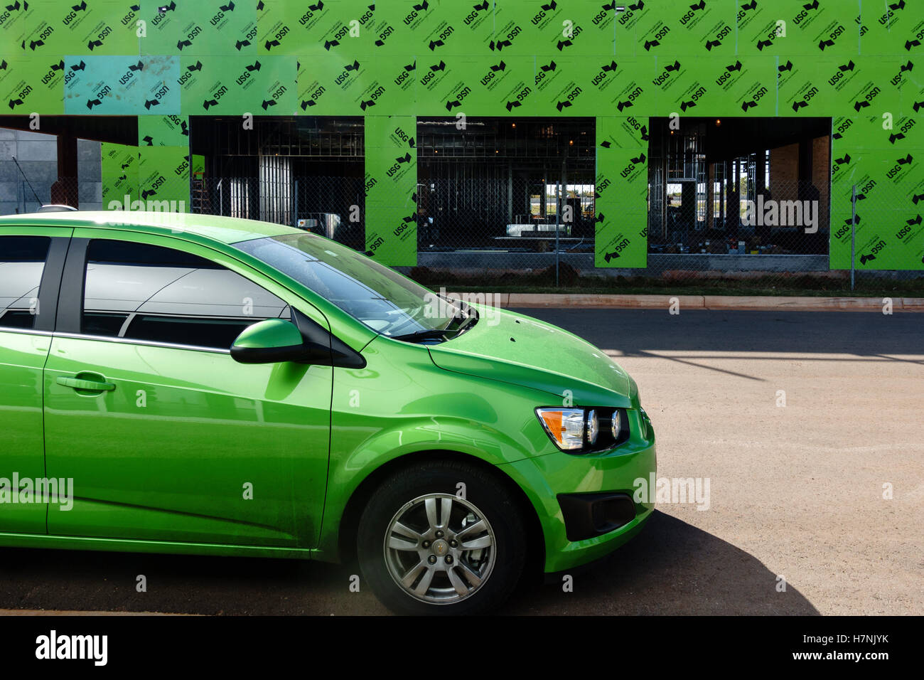 Ungewöhnliche Zusammentreffen von Lime Green passende Farben in einem Automobil und ein im Bau befindliches Gebäude. Oklahoma, USA. Stockfoto