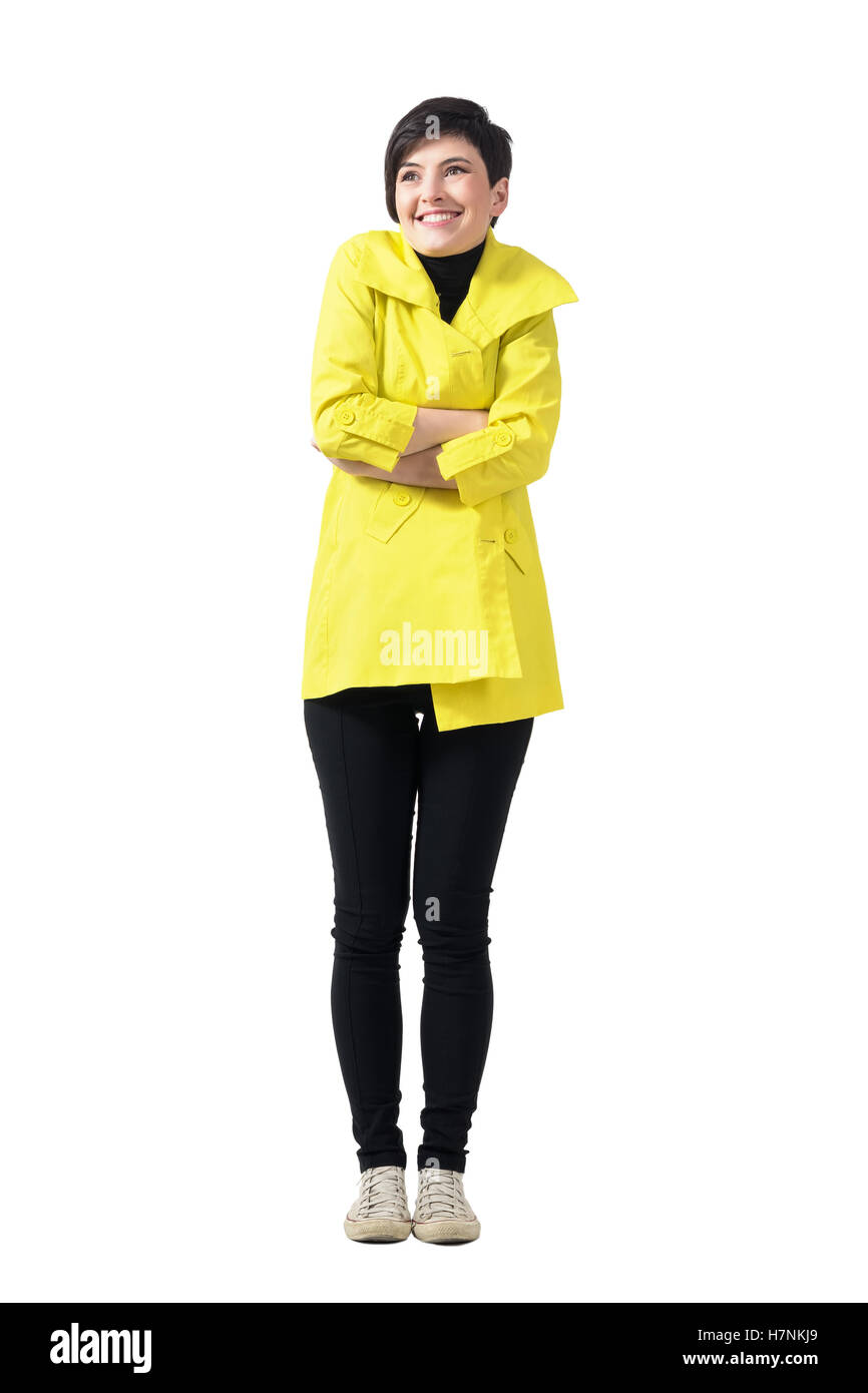 Kalten eisigen Frau trägt gelbe Mantel mit gekreuzten Armen nach oben. Ganzkörper-Länge-Porträt isoliert auf weißem Hintergrund Stockfoto