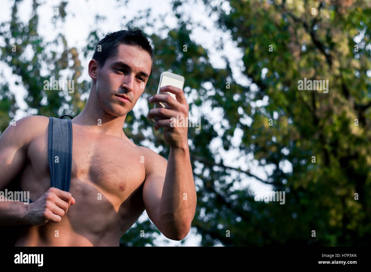 Portrait von Personaltrainer Mann im Park nach Fitnesstraining und Prüfung Sport app auf seinem Smartphone. Stockfoto