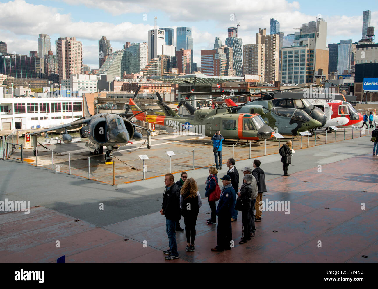 New York City hinter Touristen und Museum Flugzeuge des Flugzeugträgers USS Intrepid, Harrier jump Jet und Hubschrauber Stockfoto