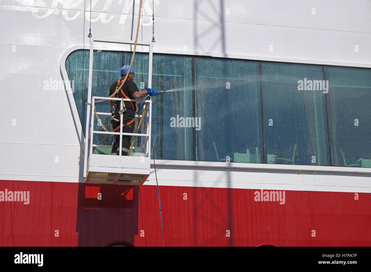 Mann in einer Wiege Fensterputzen einer Kreuzfahrt Schiff. Stockfoto