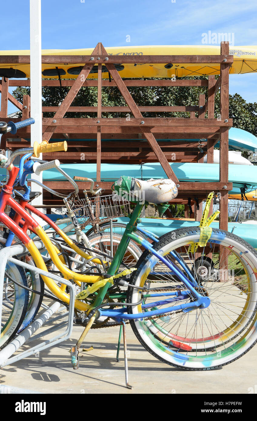 Bunte Fahrräder in einem Motorrad stehen mit einem Kajak-Rack im Hintergrund in Dana Point Harbor, Kalifornien. Stockfoto