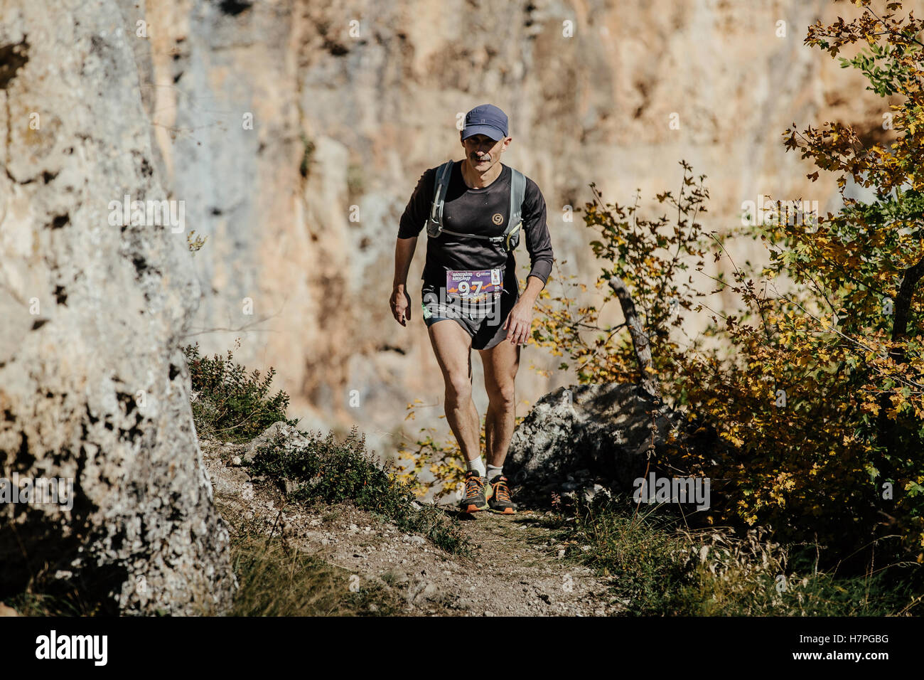 Mann mittleren Alters läuft auf einem Trail mit Rucksack während Crimea Mountain Marathon laufen Stockfoto