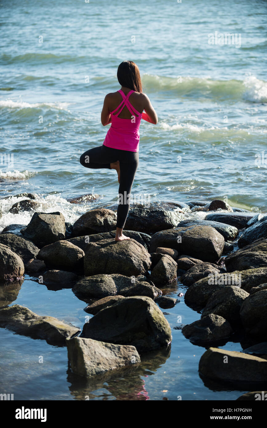 Rückansicht der Frau, die Durchführung von Yoga auf Felsen Stockfoto