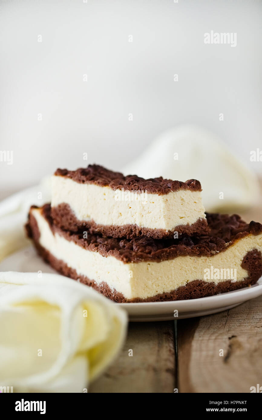 Stück Käsekuchen mit Schoko Mürbeteig und Schokolade zerbröckeln. Holztisch. Weiße Freiraum Hintergrund. Stockfoto