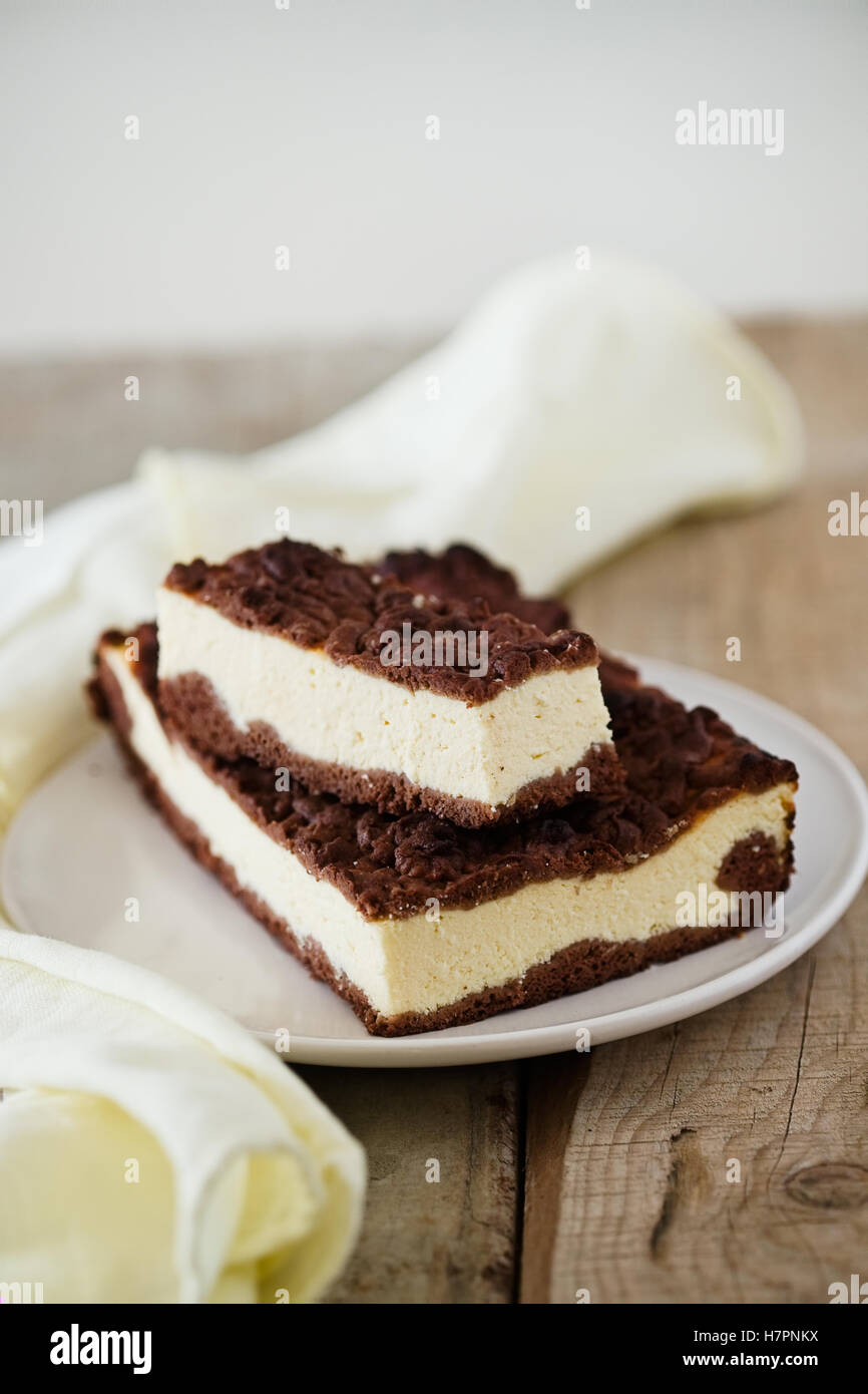 Stück Käsekuchen mit Schoko Mürbeteig und Schokolade zerbröckeln. Hölzerne Hintergrund Stockfoto