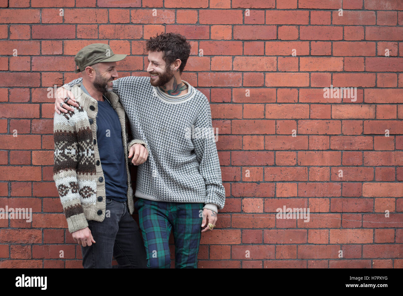 Gay paar kuscheln und lachen vor Backsteinmauer Stockfoto