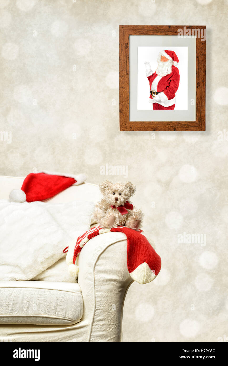 Foto von Santa Claus in Holzrahmen mit Blick auf Teddy auf sofa Stockfoto