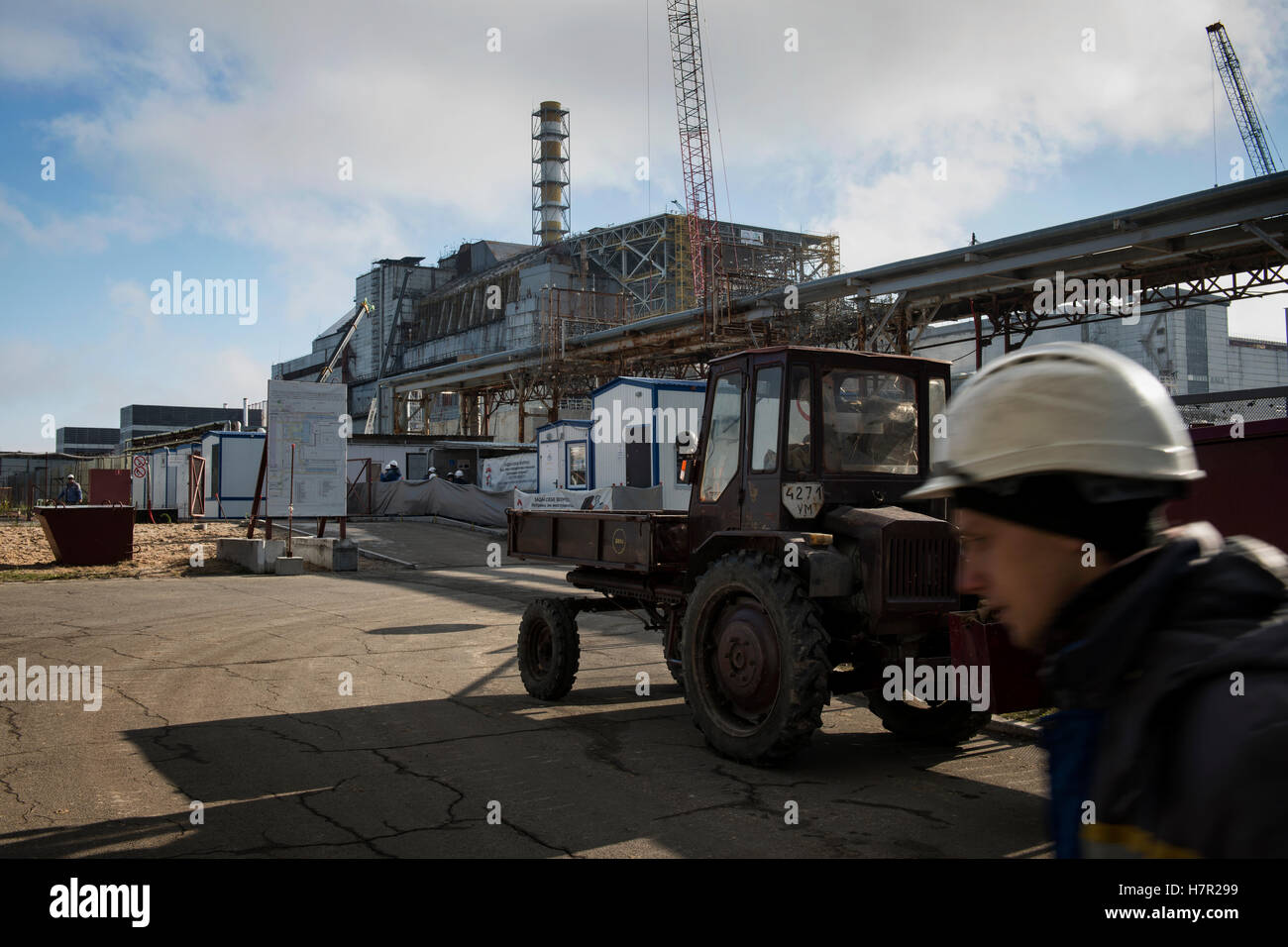 Ein Arbeiter der das neue sichere Entbindung vorbei an den zerstörten Reaktor Nr. 4 mit seiner alten einschließenden Sarkophag. Kernkraftwerk, Ukraine. Stockfoto