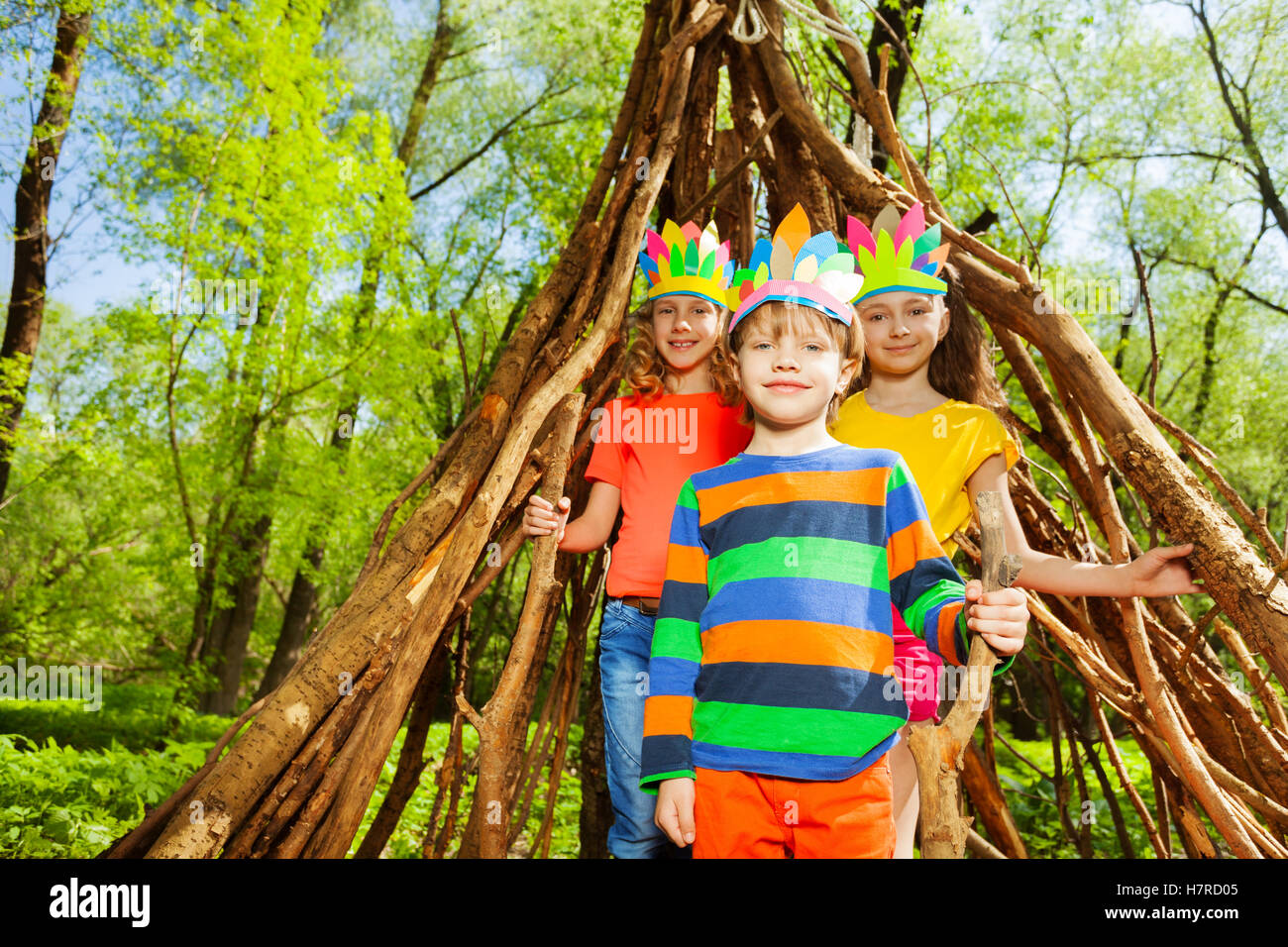 Drei glückliche Kinder spielen Injuns im Wald Stockfoto