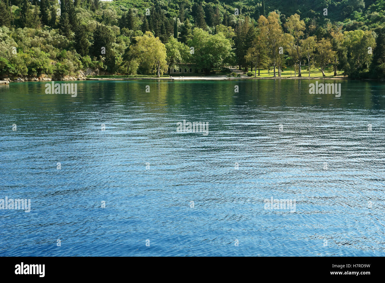 Skorpios, Griechenland, 11. Mai 2013: Landschaft mit grünen Garten und Häuschen in der Bucht auf der griechischen Insel. Ionisches Meer, Griechenland. Stockfoto