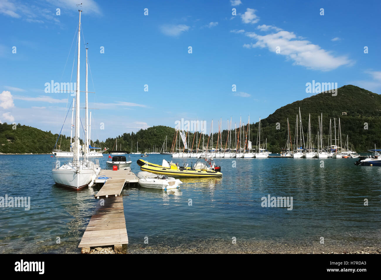 Nidri, Griechenland, 11. Mai 2013: Landschaft mit blauen Hafen, grüne Küste, Berge und Yachten im Ionischen Meer, Griechenland. Stockfoto