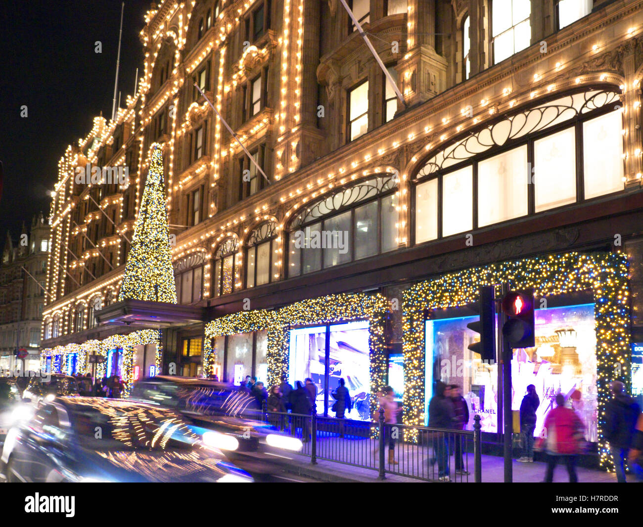 HARRODS WEIHNACHTSBAUM SHOPPING SHOPPER LONDON Harrods Kaufhaus in der Abenddämmerung mit Weihnachtslichtern Shopping Menschenmassen und vorbeifahrenden Autos Knightsbridge London SW1 Stockfoto