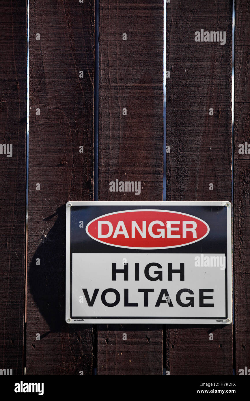 Hochspannung Warnschild am Holzzaun in einem Umspannwerk in Neuseeland Stockfoto