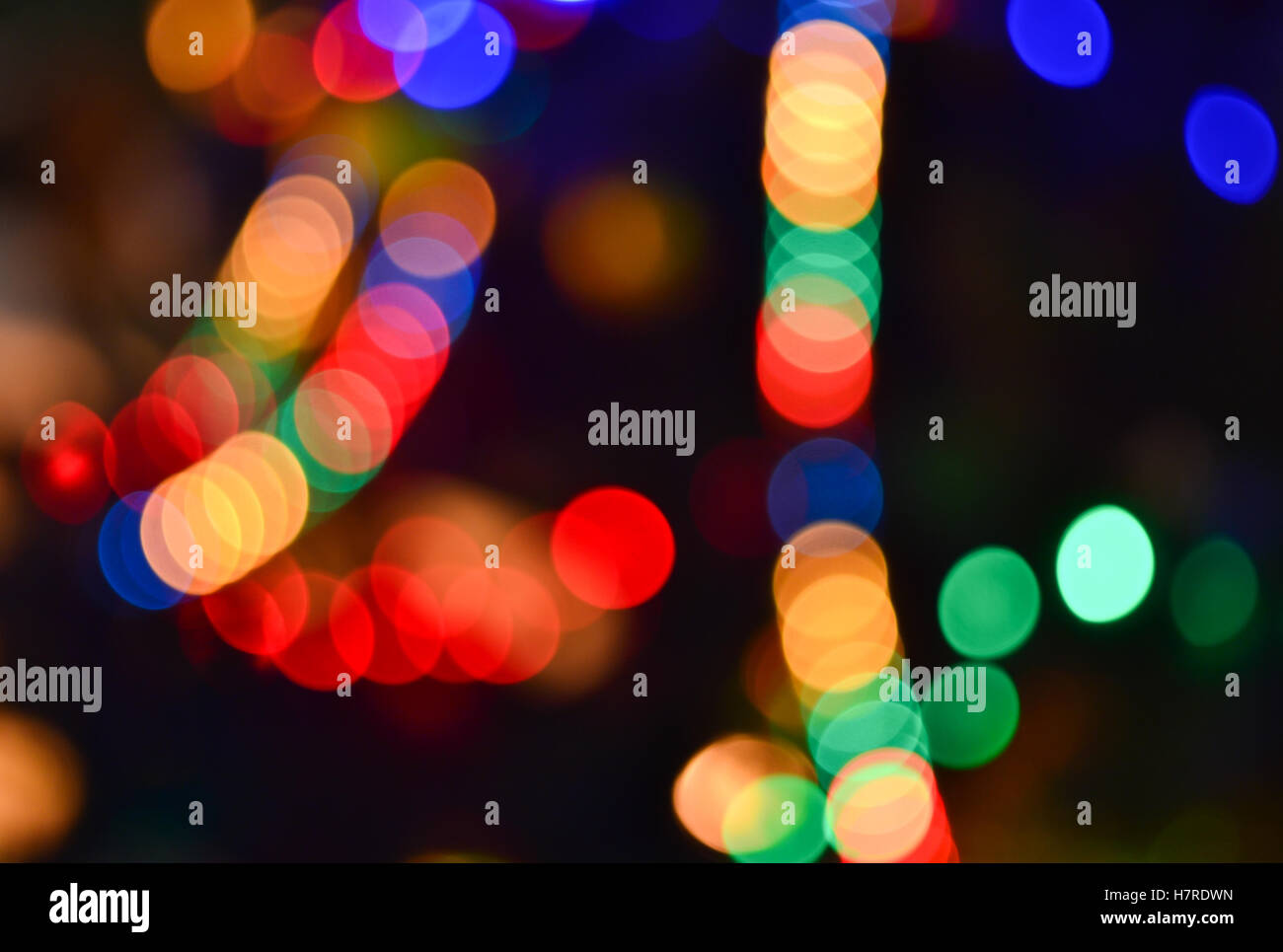 Christmas Lights Hintergrund. Verschwommene elektrische Girlande am Weihnachtsbaum. Rot, grün, gelb, orange und blau leuchten im Dunkeln Stockfoto