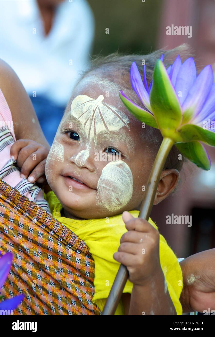Yangon, Myanmar - 16. November 2014.  Junges Kind in Mutters Schlinge mit Bo-Blattentwurf Thanaka auf Stirn, Stockfoto
