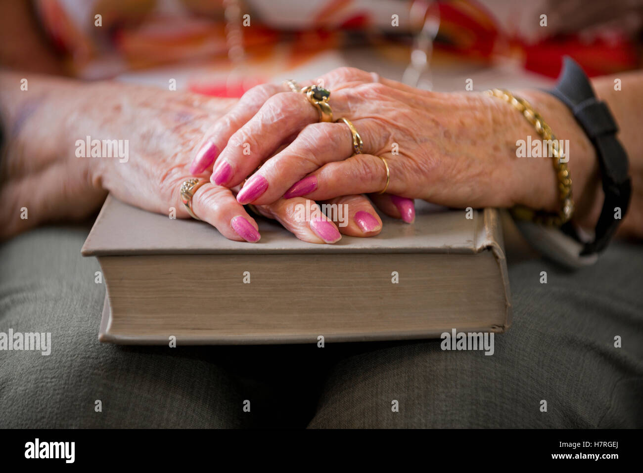 Eine ältere Frau Hände gefaltet auf ein Hardcover-Buch; Devon, Alberta, Kanada Stockfoto
