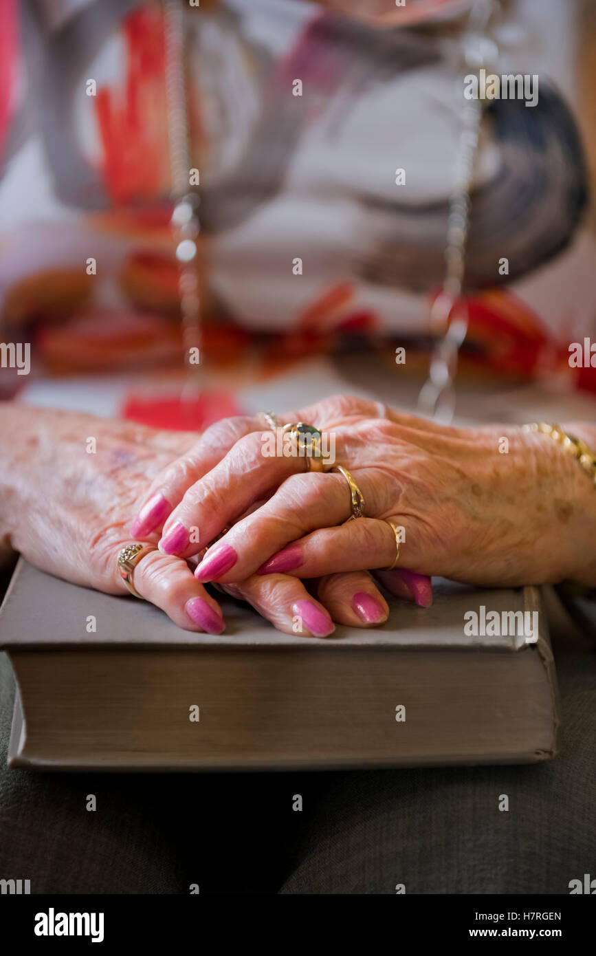 Eine ältere Frau Hände gefaltet auf ein Hardcover-Buch; Devon, Alberta, Kanada Stockfoto
