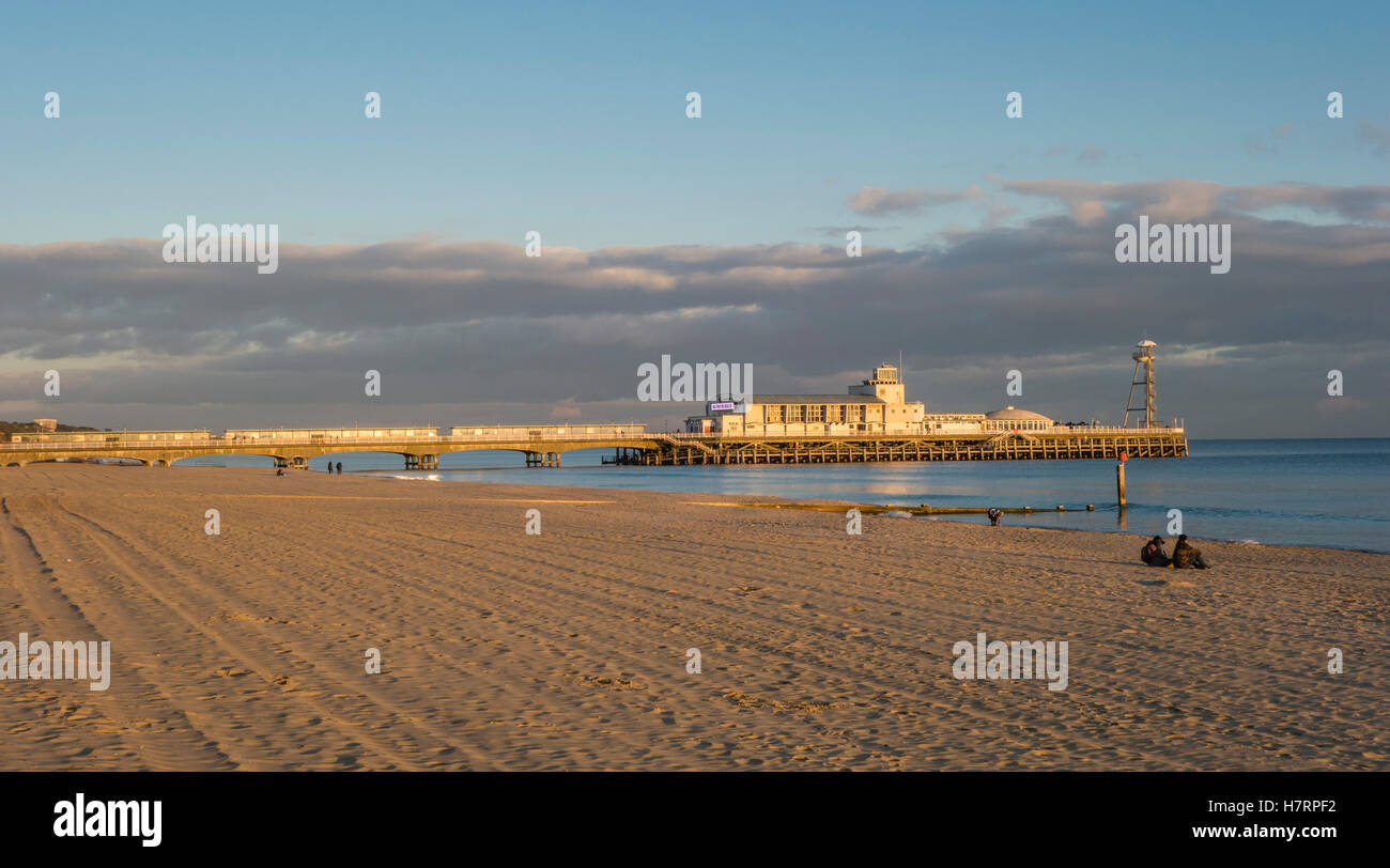 Ein paar Sitze allein am Strand genießen Sie das ruhige Meer und abends Sonnenlicht mit dem Pier im Hintergrund in Bournemouth, Großbritannien Stockfoto