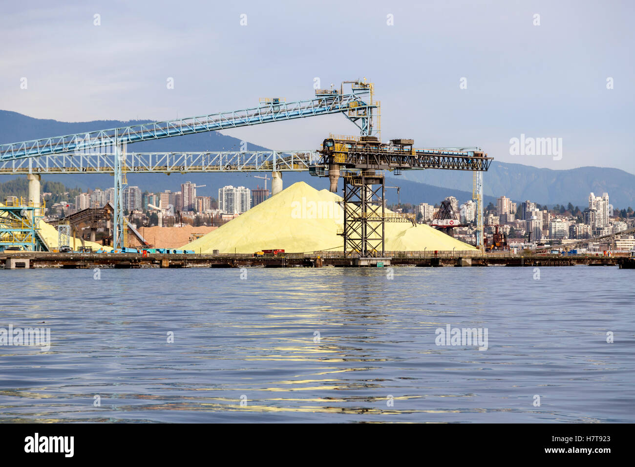 Schwefelstapel sitzen unter den Kranen und Fördergurten in Einem Vancouver Shipping Yard, Hafen von Vancouver warten auf Verladung und Transport für Ex... Stockfoto