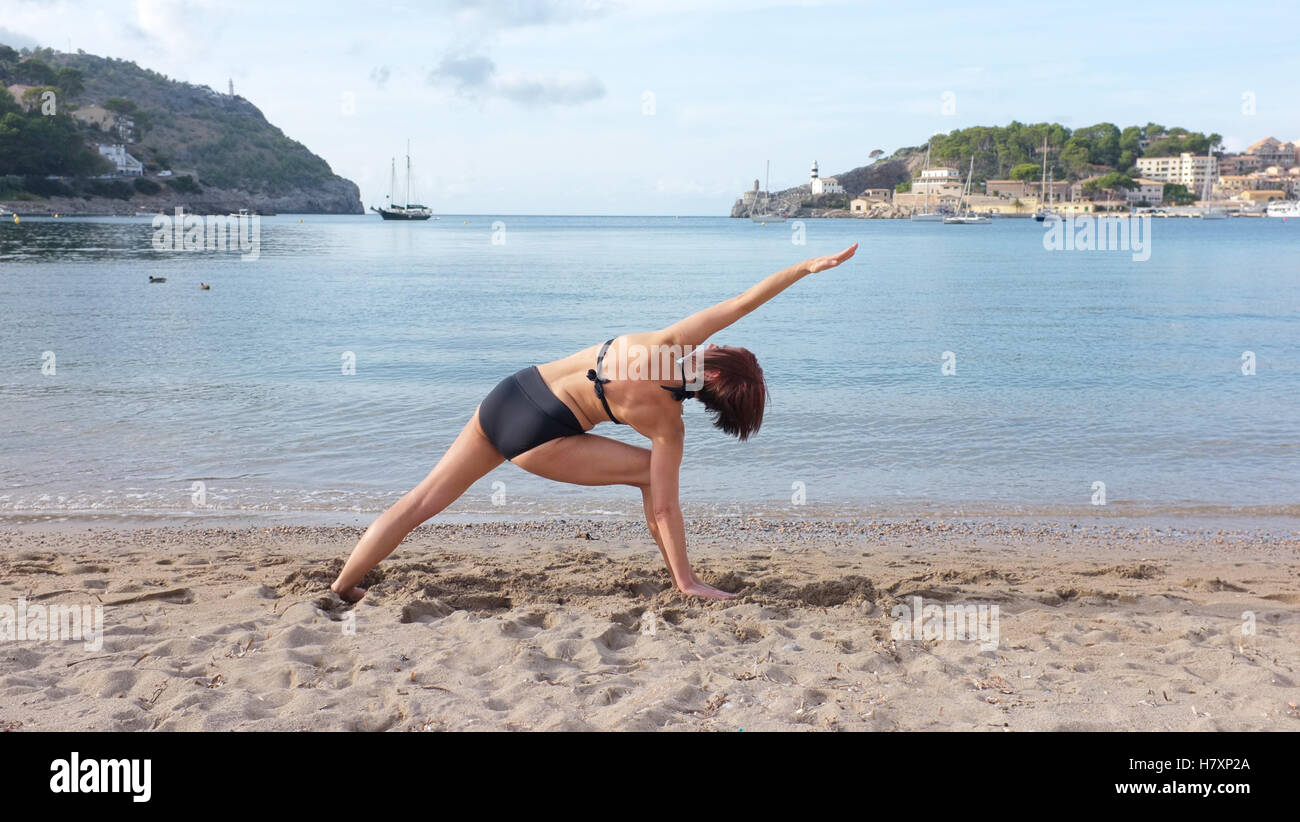 Eine Frau praktizieren Yoga an einem Strand auf Mallorca. Seitenwinkel pose 2 gezeigt Stockfoto