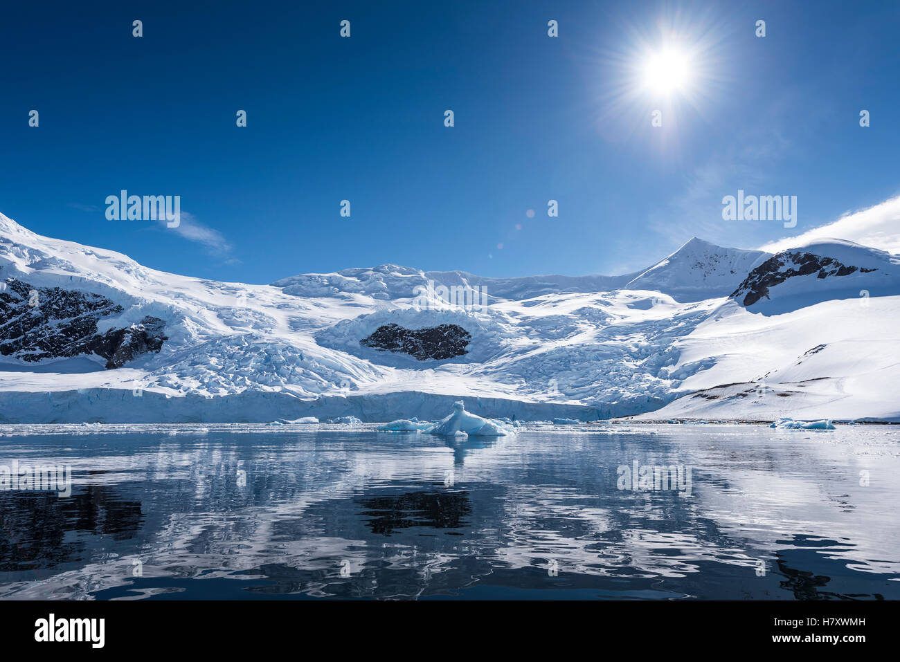 Sonne und Schnee auf den Bergen spiegelt sich im Wasser des Neko Harbour; Antarktis Stockfoto