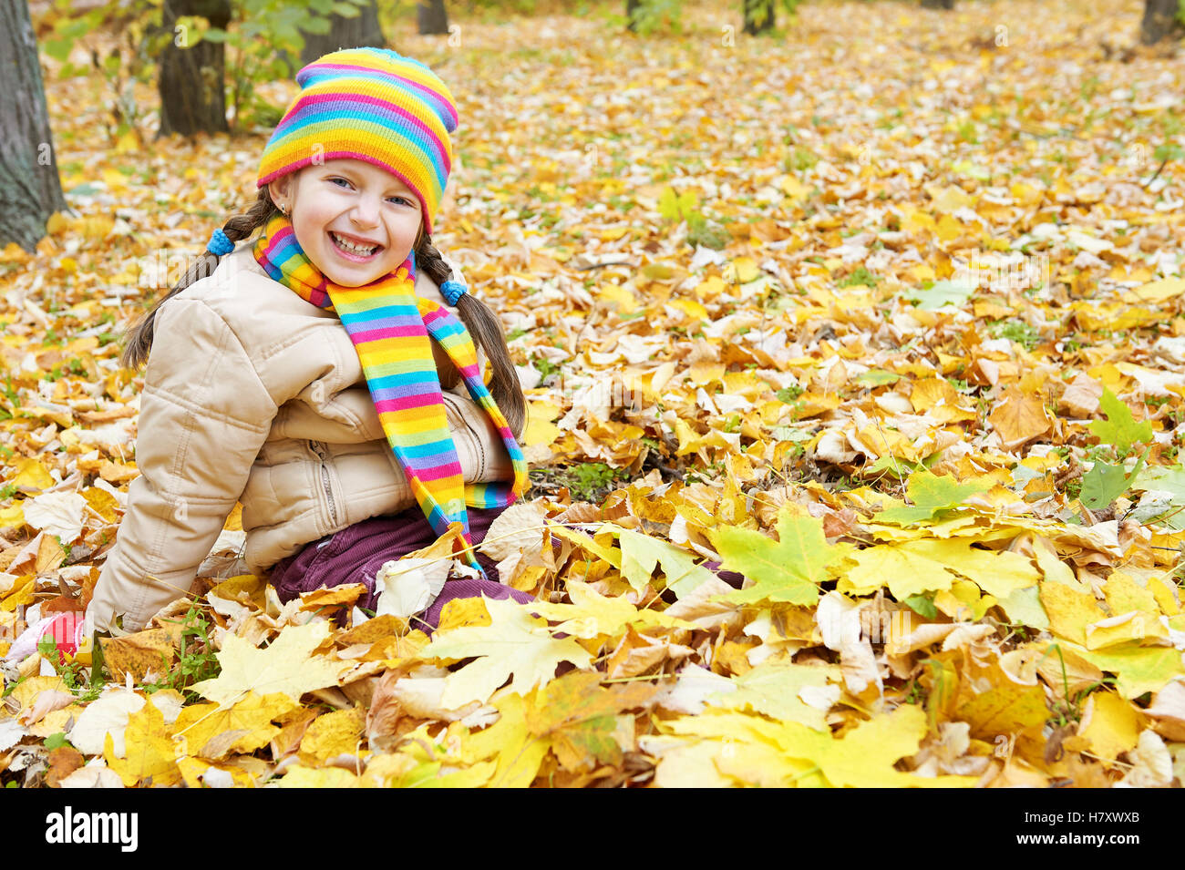 Mädchen Kind sitzen im herbstlichen Wald, Landschaft in Herbst-Saison mit gelben Blättern Stockfoto